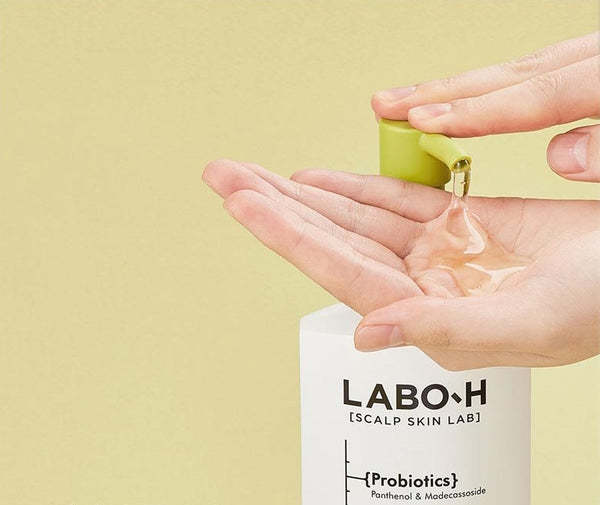 Hand holding a small container of cream above a LABO-H product with a beige background